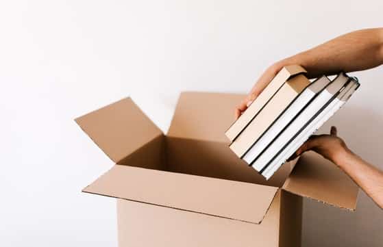 Removalists packing books into a cardboard box for a Brisbane to Sydney interstate move