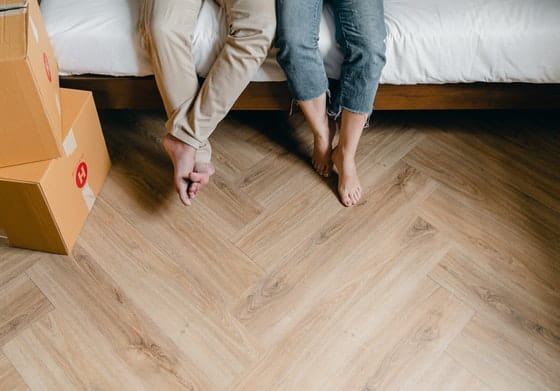 Man and Woman Sitting Barefoot on Bed — Caloundra Removals & Storage in Sunshine Coast, QLD