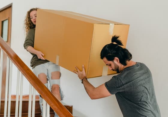 Man and Woman Carrying a Box up the Stairs — Caloundra Removals & Storage in Sunshine Coast, QLD