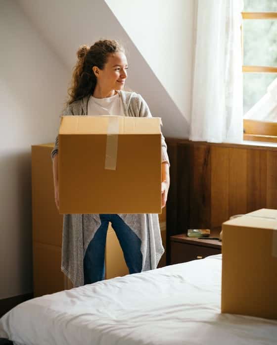 Smiling Woman Carrying Moving Box — Caloundra Removals & Storage in Sunshine Coast, QLD