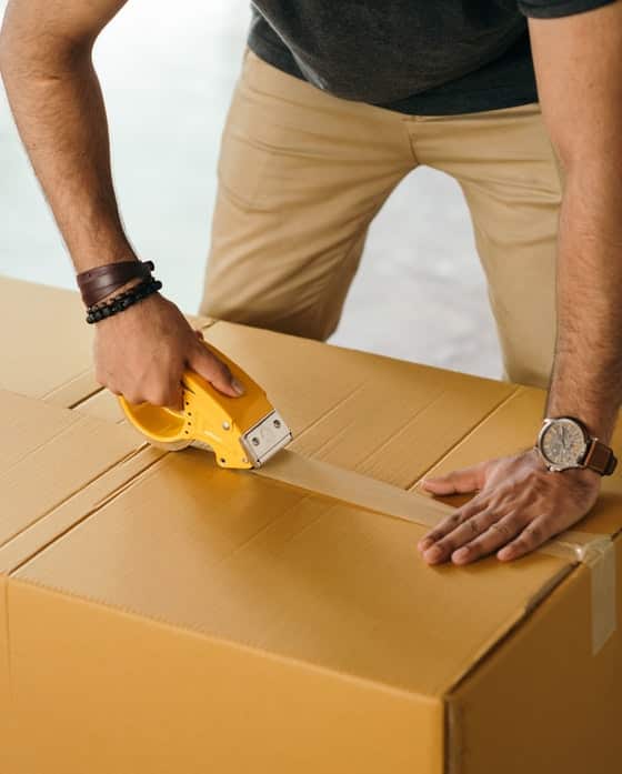 Man Sealing a Box With Packing Tape Dispenser — Caloundra Removals & Storage in Sunshine Coast, QLD