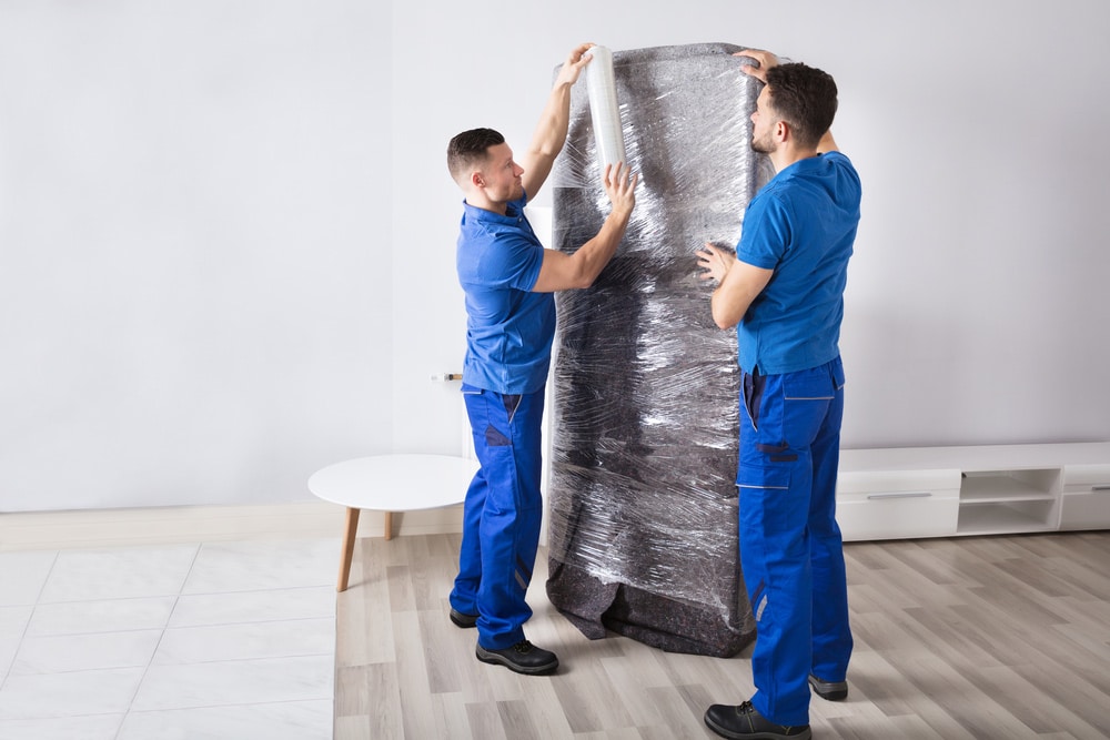 Two Young Male Movers Packing Furniture