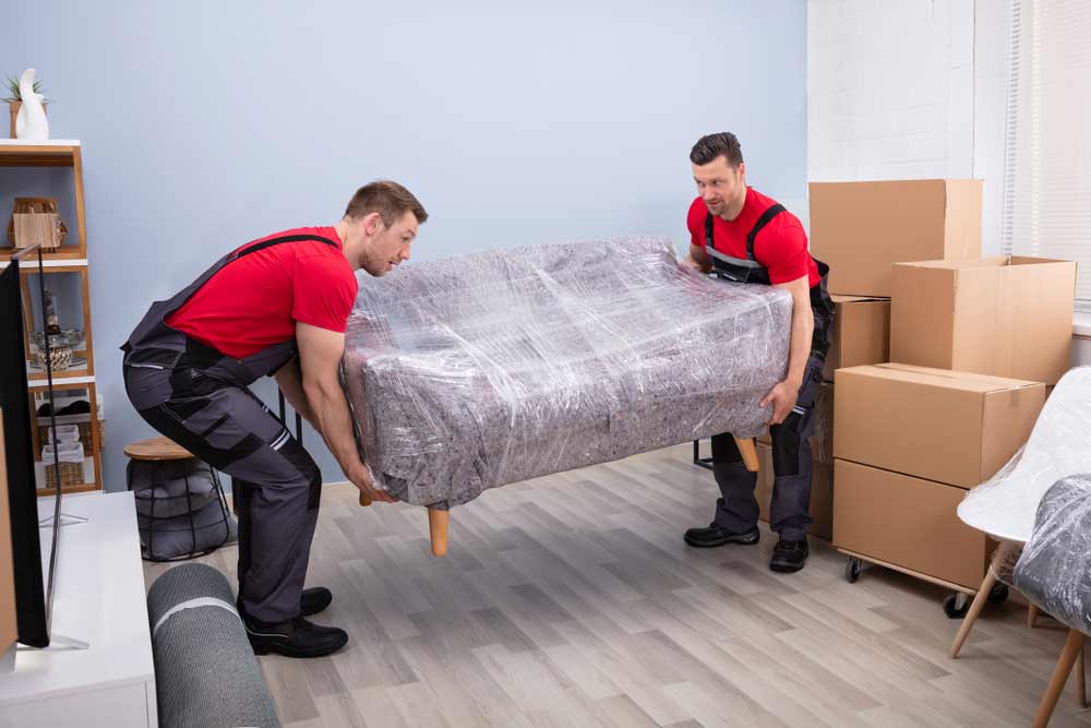 Two Movers In Red Shirt Lifting A Sofa